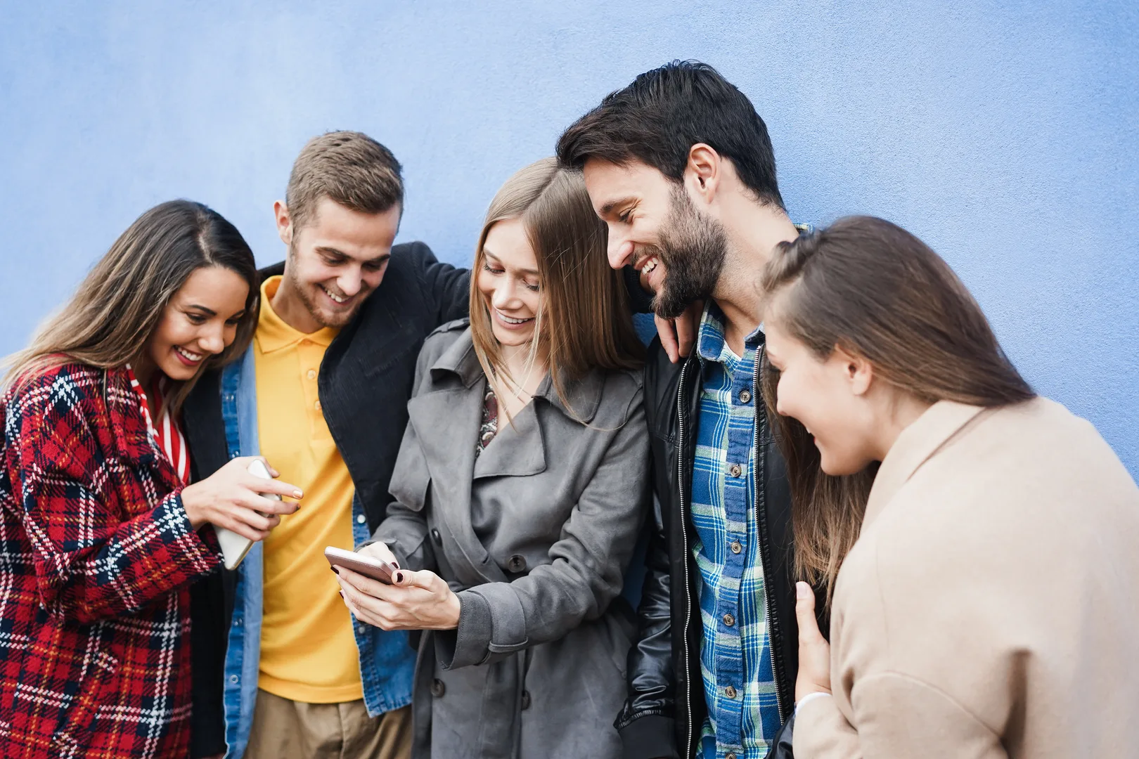 Young friends having fun using mobile phones outdoors in the city