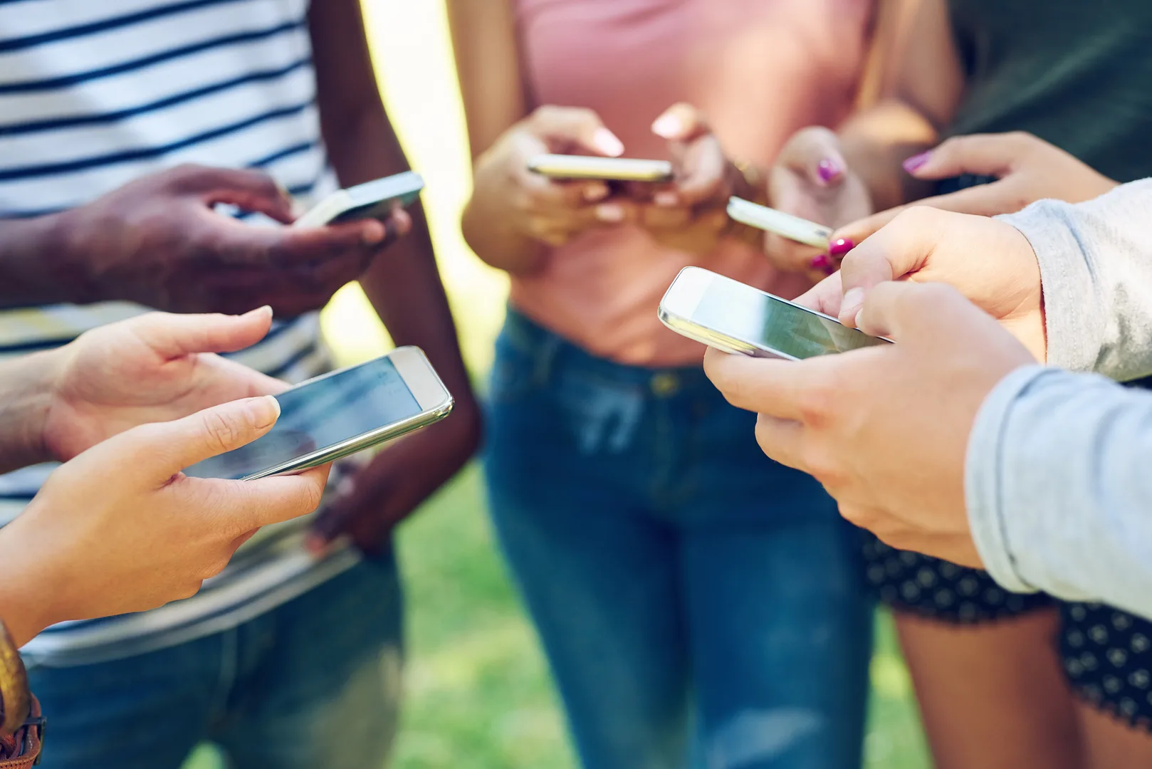 Cropped shot of a group of friends using their phones together